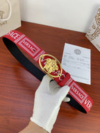 Versace belt with red fabric strap, gold Medusa oval buckle, and repeating logo trim.