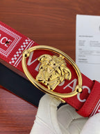 Versace belt close-up: gold oval Medusa buckle on red fabric strap with logo pattern.