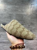 Beige patterned slide sandal held in hand, sole edge and black insole visible