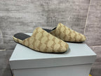 Pair of beige patterned slide sandals on white box, angled top view