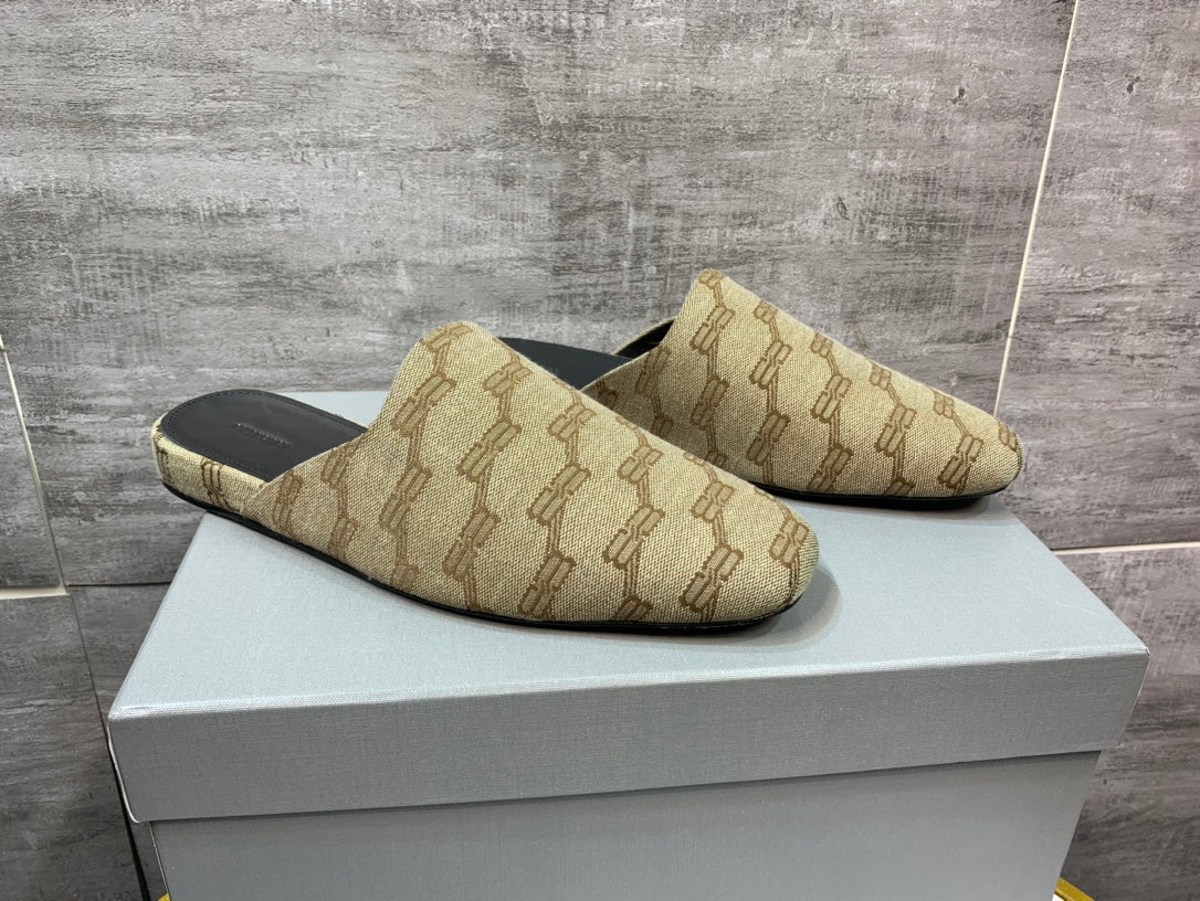 Pair of beige patterned slide sandals on white box, angled top view