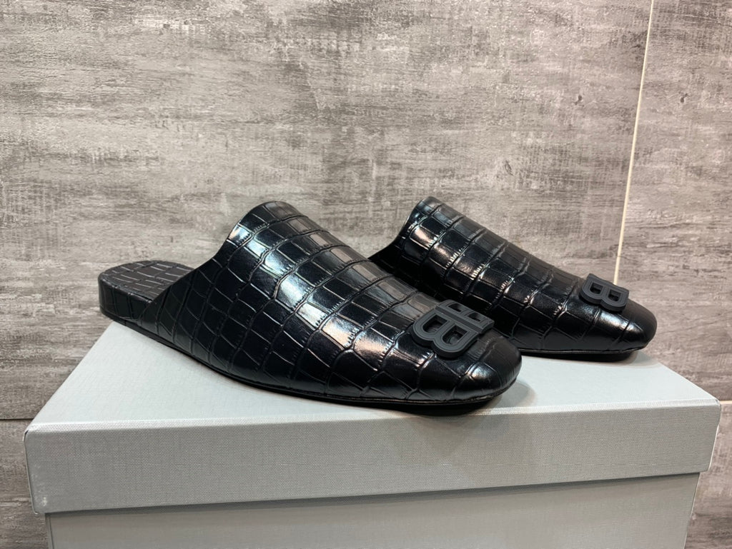 Black croc-embossed slide sandals pair on box, side-by-side