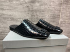 Black croc-embossed slide sandals pair on box, side-by-side