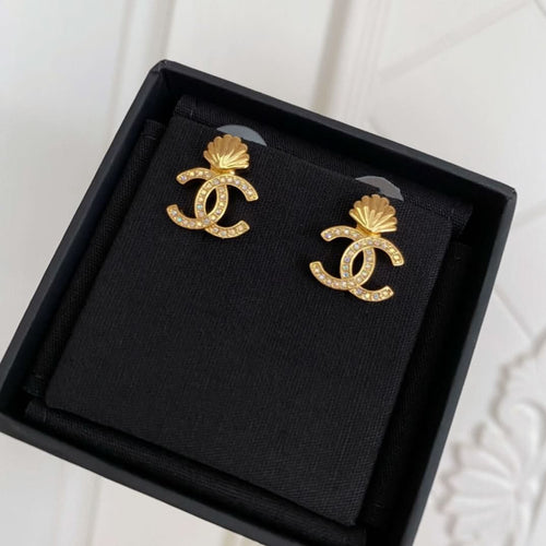 Chanel stud earrings set in black box, gold-tone CC shell design