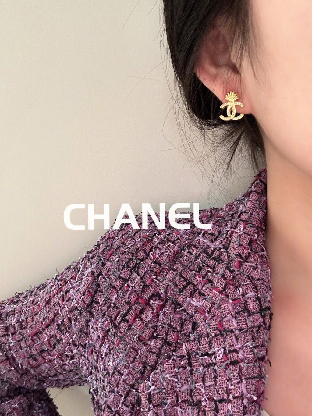 Chanel stud earrings with gold-tone CC shell motif worn on ear