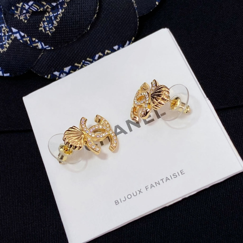 Chanel stud earrings with gold-tone CC and shell motif on a display card