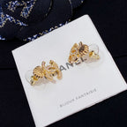 Chanel stud earrings with gold-tone CC and shell motif on a display card