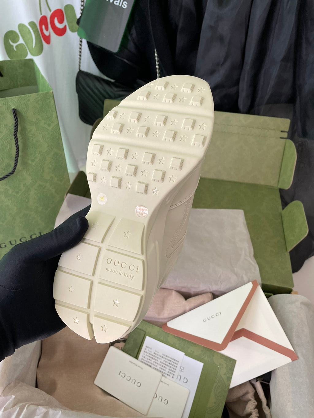 Cream Gucci sneaker outsole view with textured tread and logo marks.