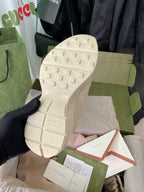 Cream Gucci sneaker outsole view with textured tread and logo marks.