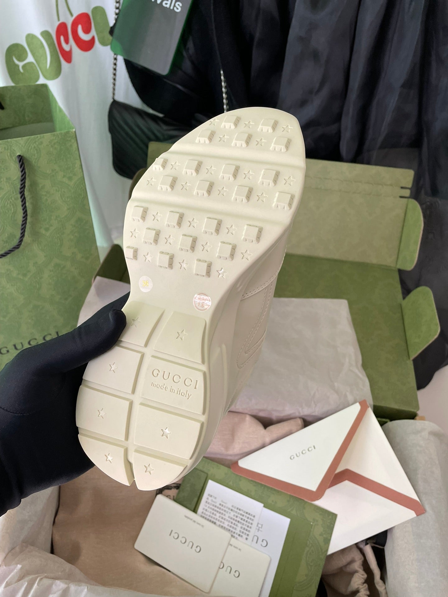 Cream Gucci sneaker outsole view with textured tread and logo marks.