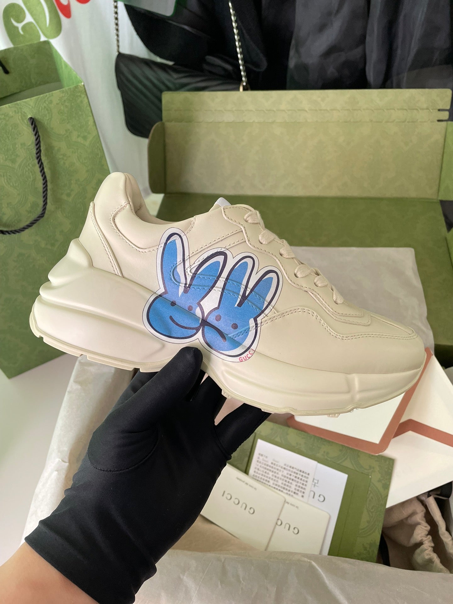 Cream Gucci lace-up sneakers with blue rabbit graphic on the side.