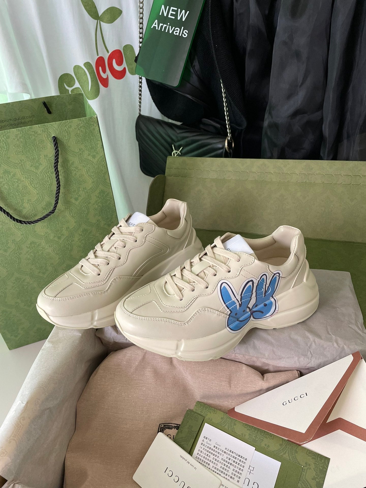 Cream Gucci sneakers set with blue rabbit graphic and lace-up front.