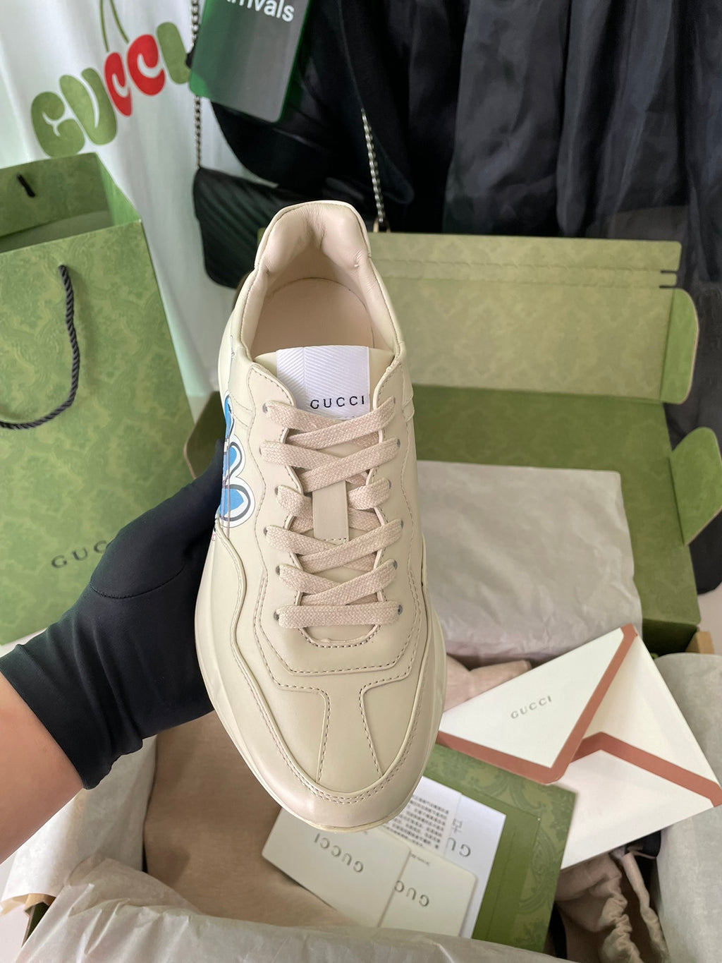 Cream Gucci lace-up sneakers with blue rabbit logo on the outer side.