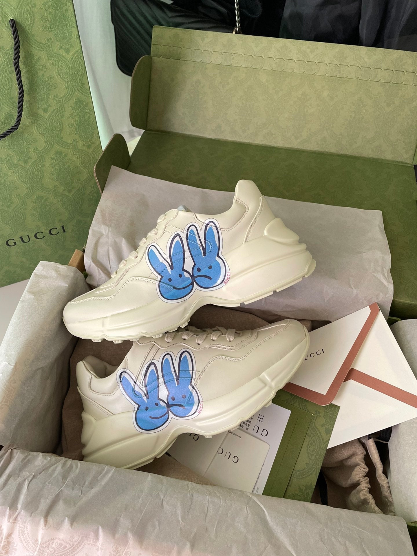 Pair of cream Gucci lace-up sneakers with blue rabbit graphics.