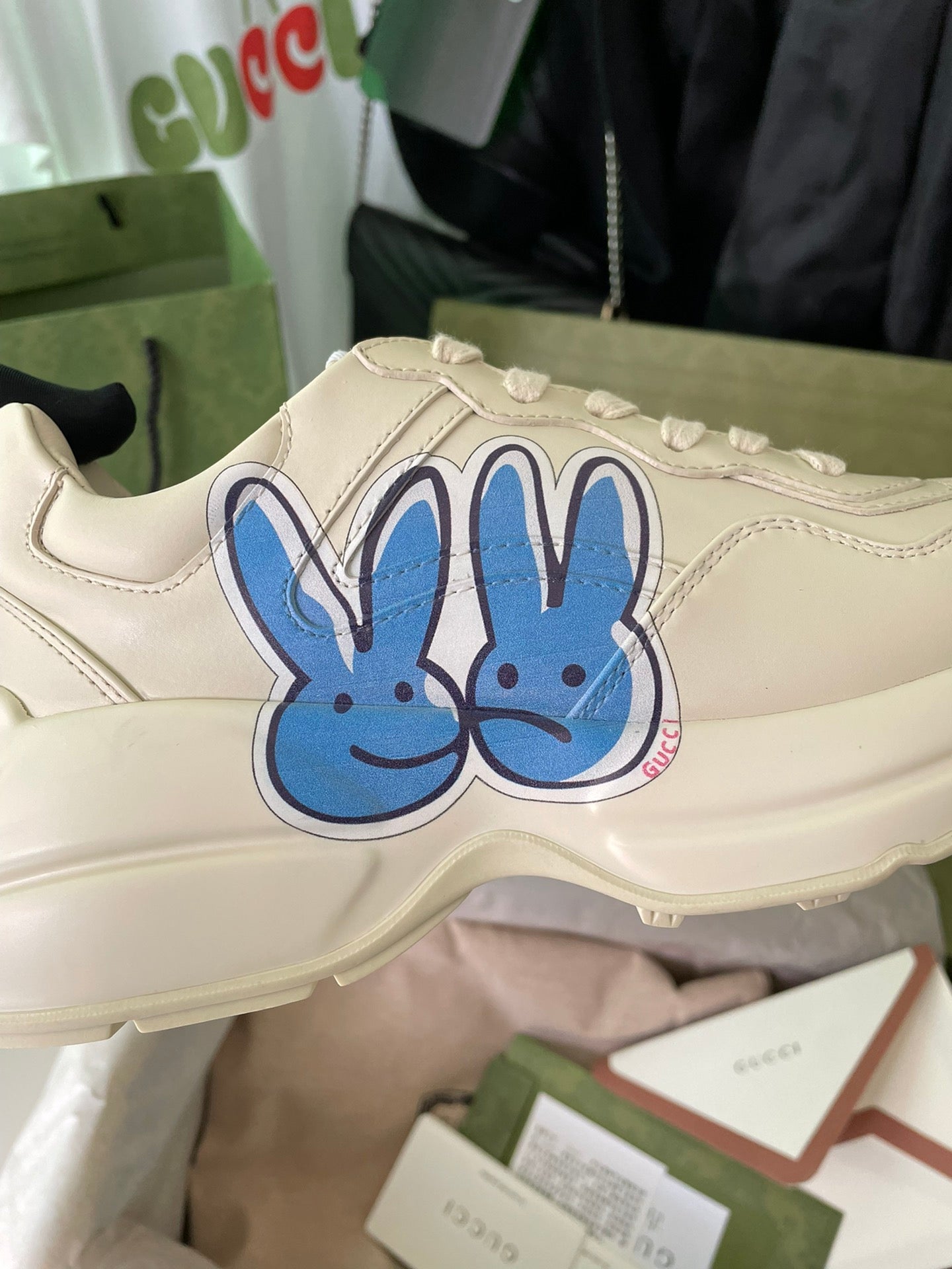 Cream Gucci sneakers close-up with large blue rabbit graphic on the side.