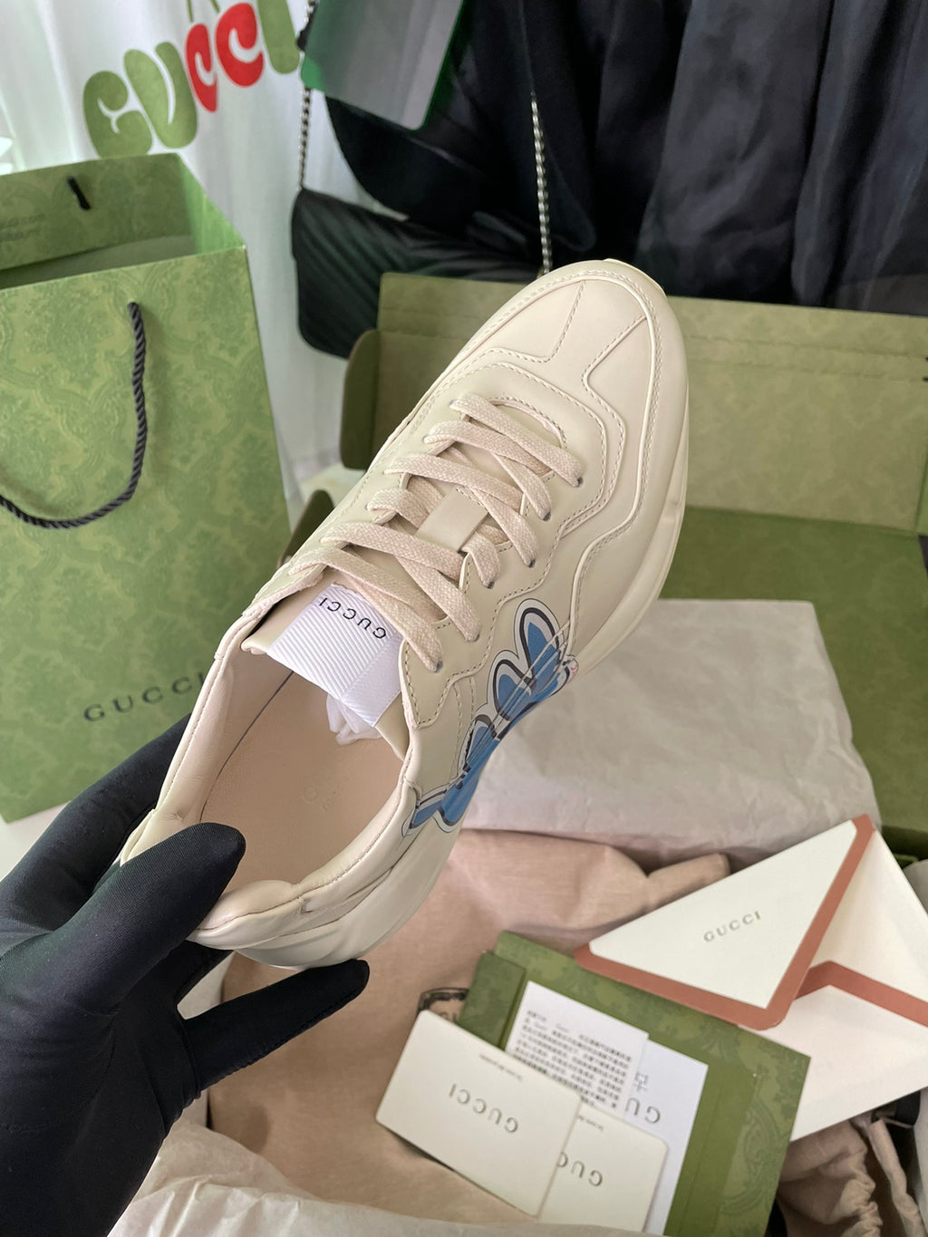 Cream Gucci lace-up sneakers with blue rabbit graphic and white laces.