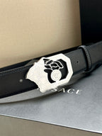 Dark blue leather belt with silver Medusa emblem buckle, close-up.
