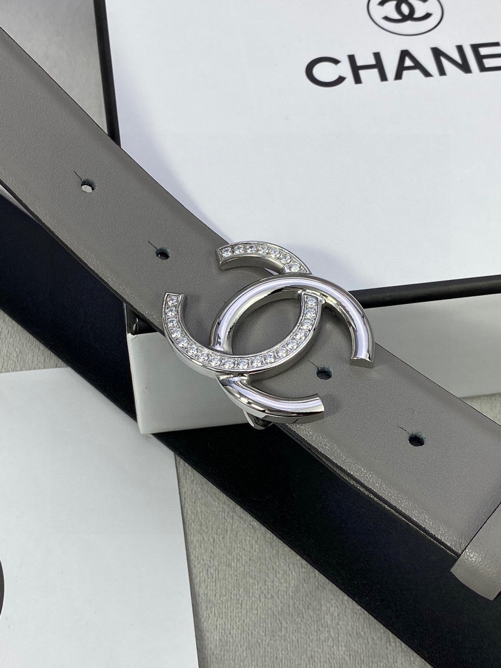 Gray leather belt with silver-tone double C buckle with rhinestones, side view detail