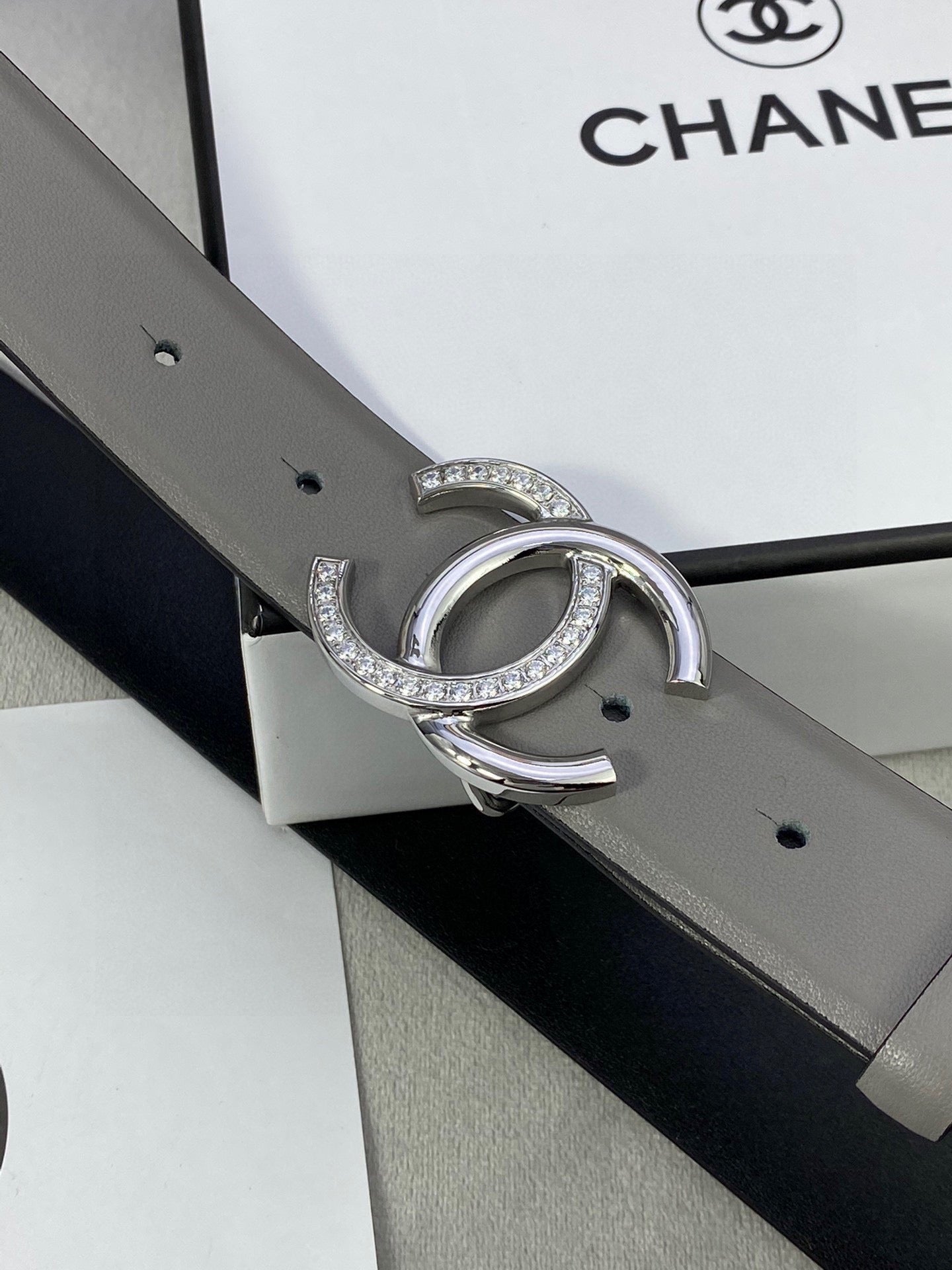 Gray leather belt with silver-tone double C buckle with rhinestones, side view detail