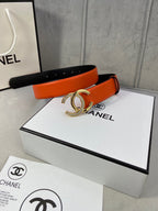 Orange leather belt with black underside and gold-tone CC buckle on box