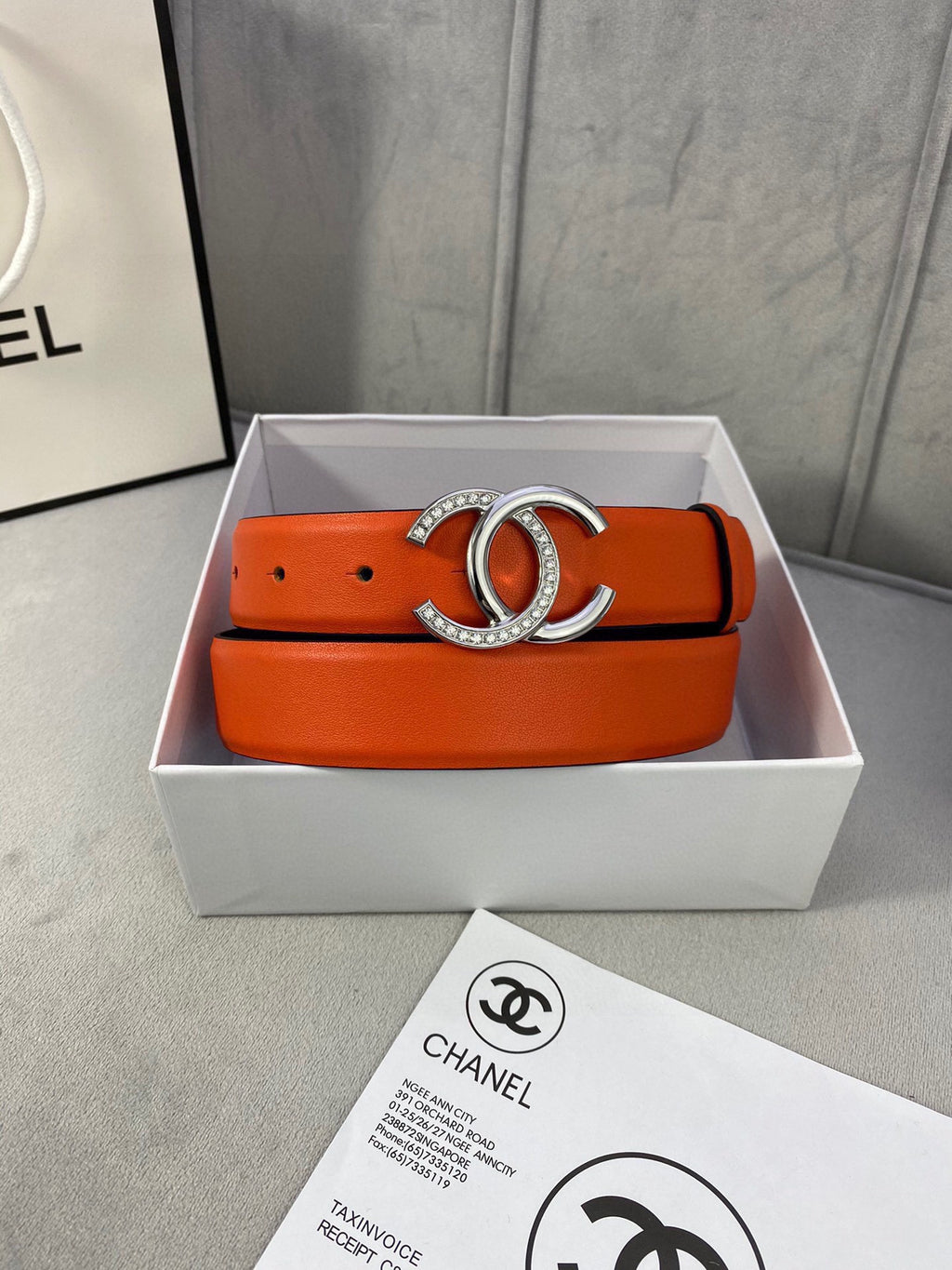 Orange leather belt with silver rhinestone CC buckle in a white gift box