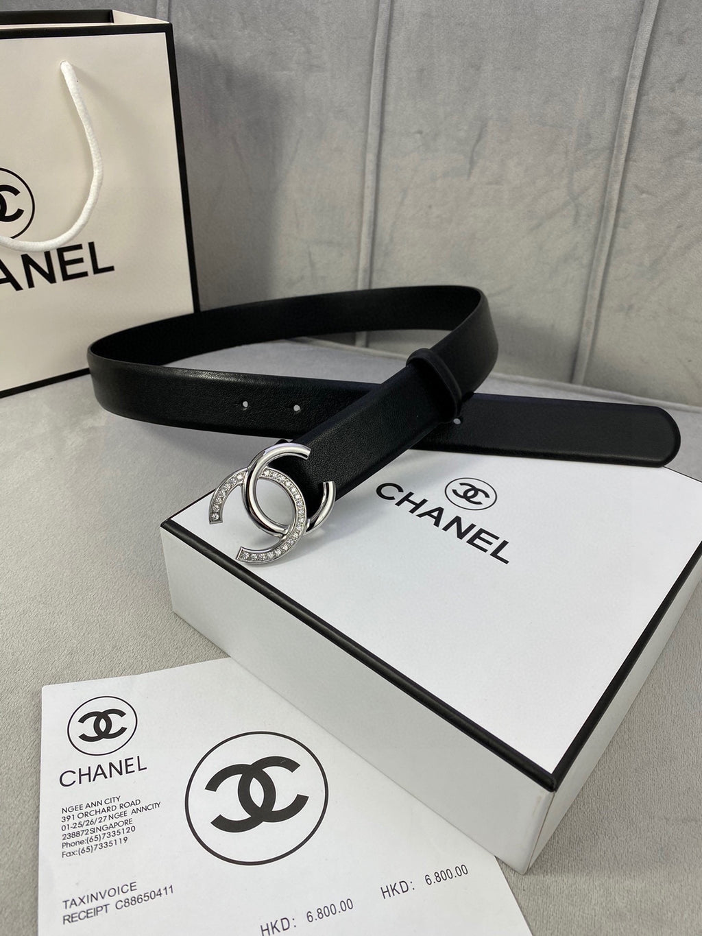 Black leather belt with silver-tone CC buckle resting on box