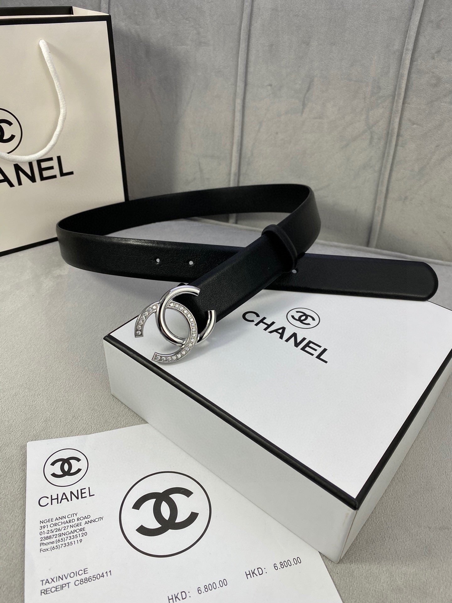 Black leather belt with silver-tone CC buckle resting on box