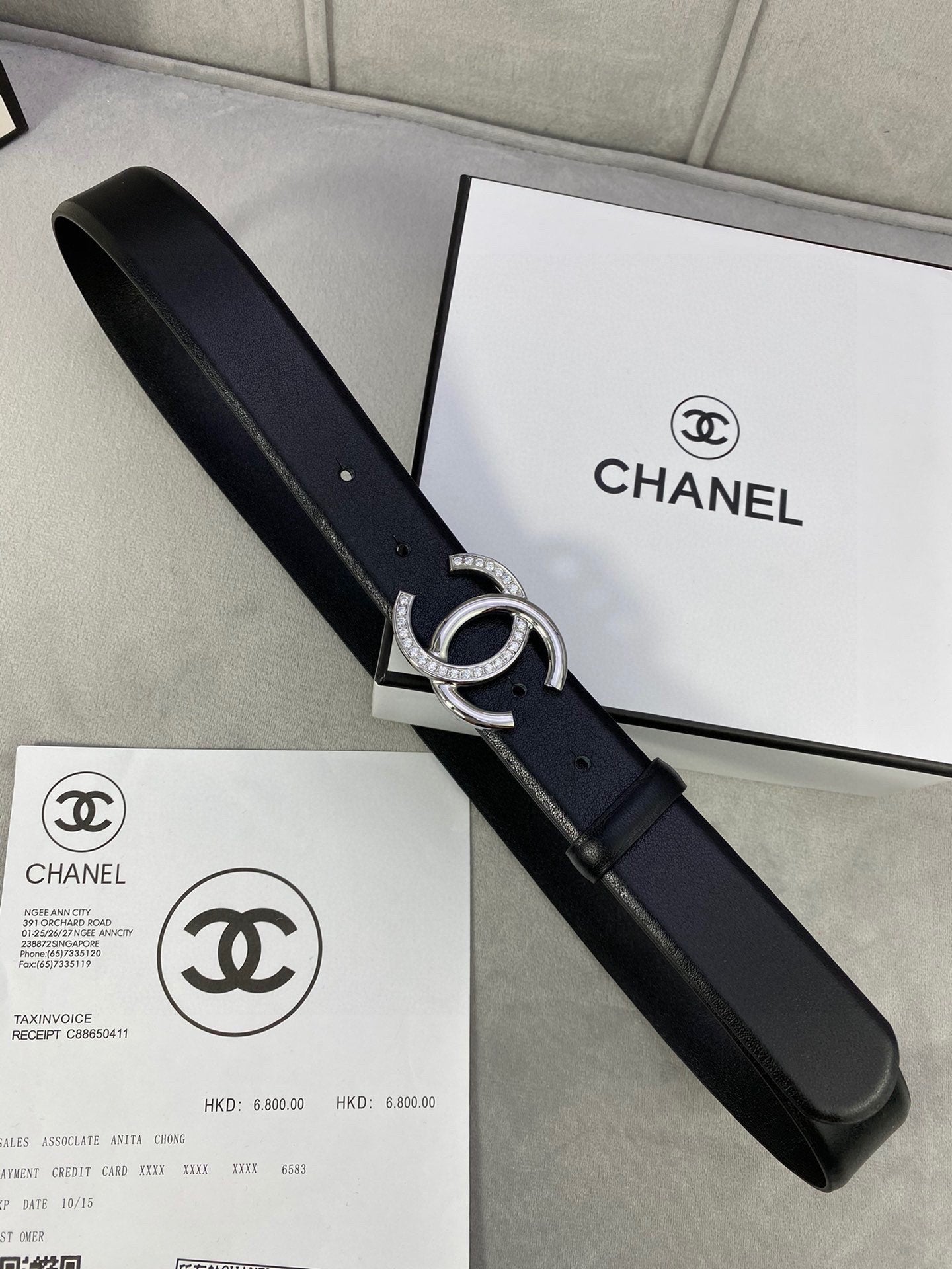 Black leather belt with silver-tone CC buckle on packaging