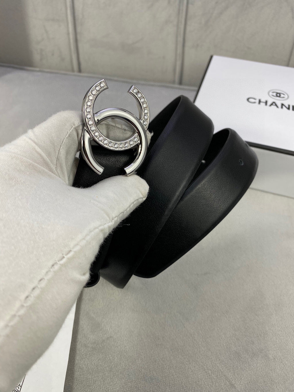 Black leather belt with silver-tone CC buckle, strap in hand