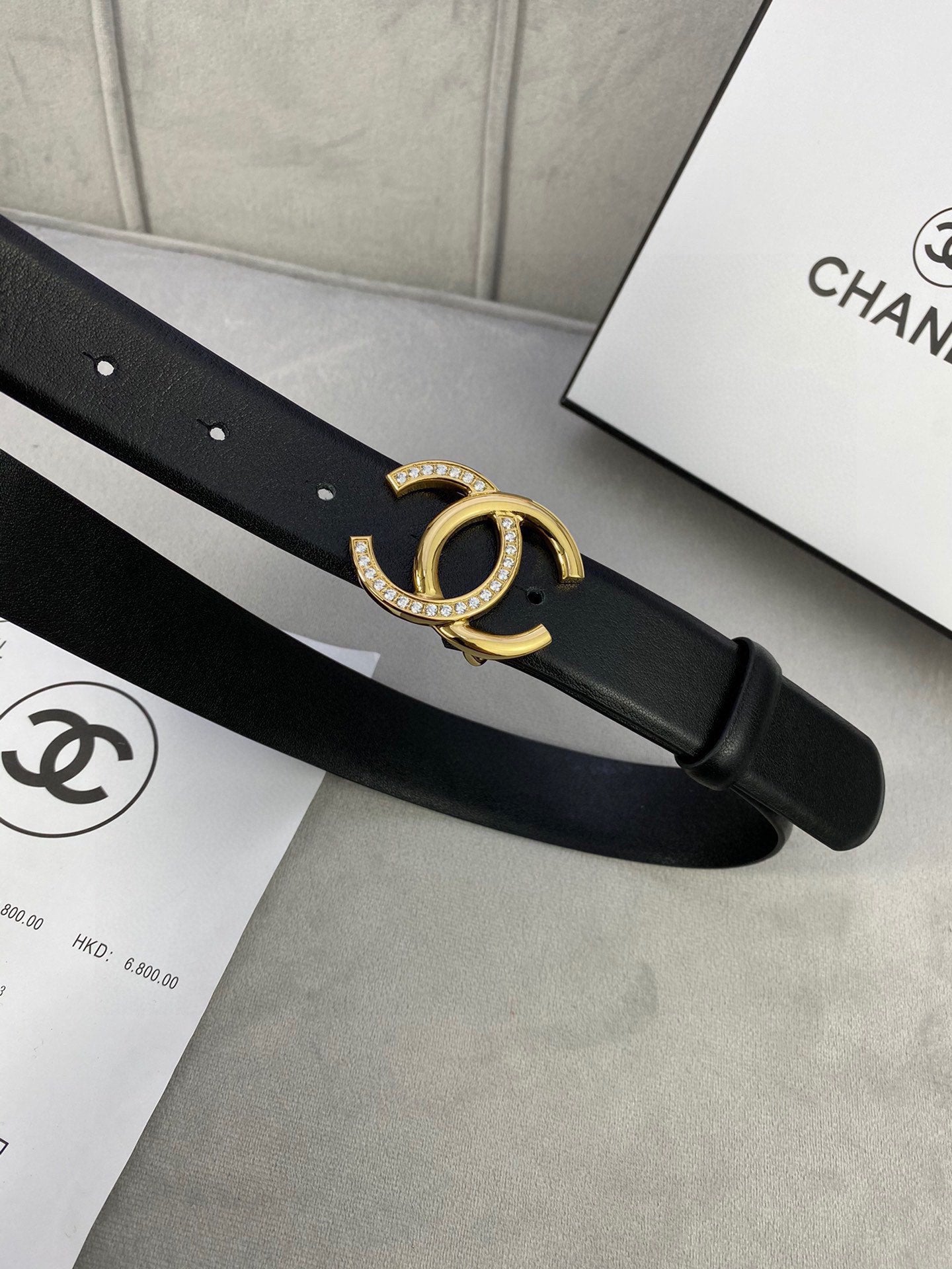 Black leather belt close-up of gold-tone CC buckle on strap