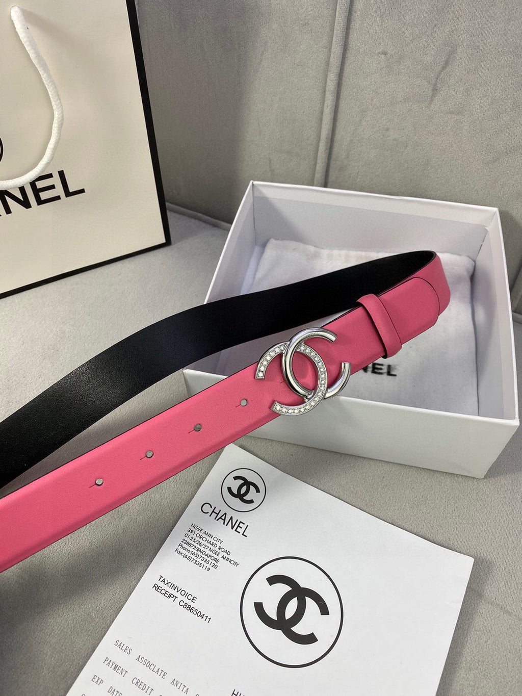 Chanel belt in pink with black underside and gold CC buckle, shown in gift box