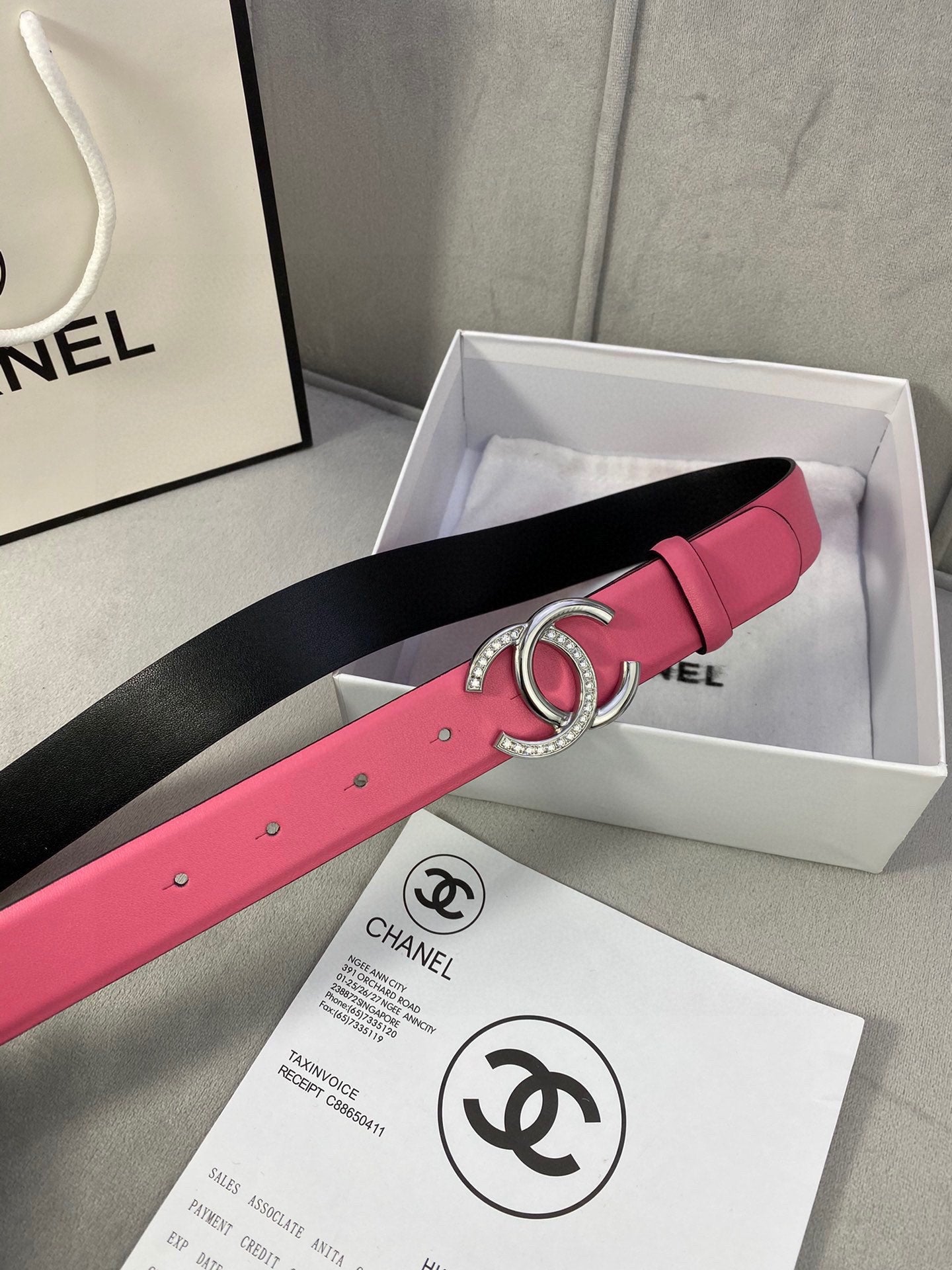 Chanel belt in pink with black underside and gold CC buckle, shown in gift box
