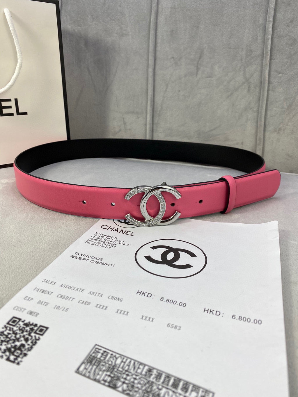 Chanel belt with pink leather strap, black underside, and gold rhinestone CC buckle