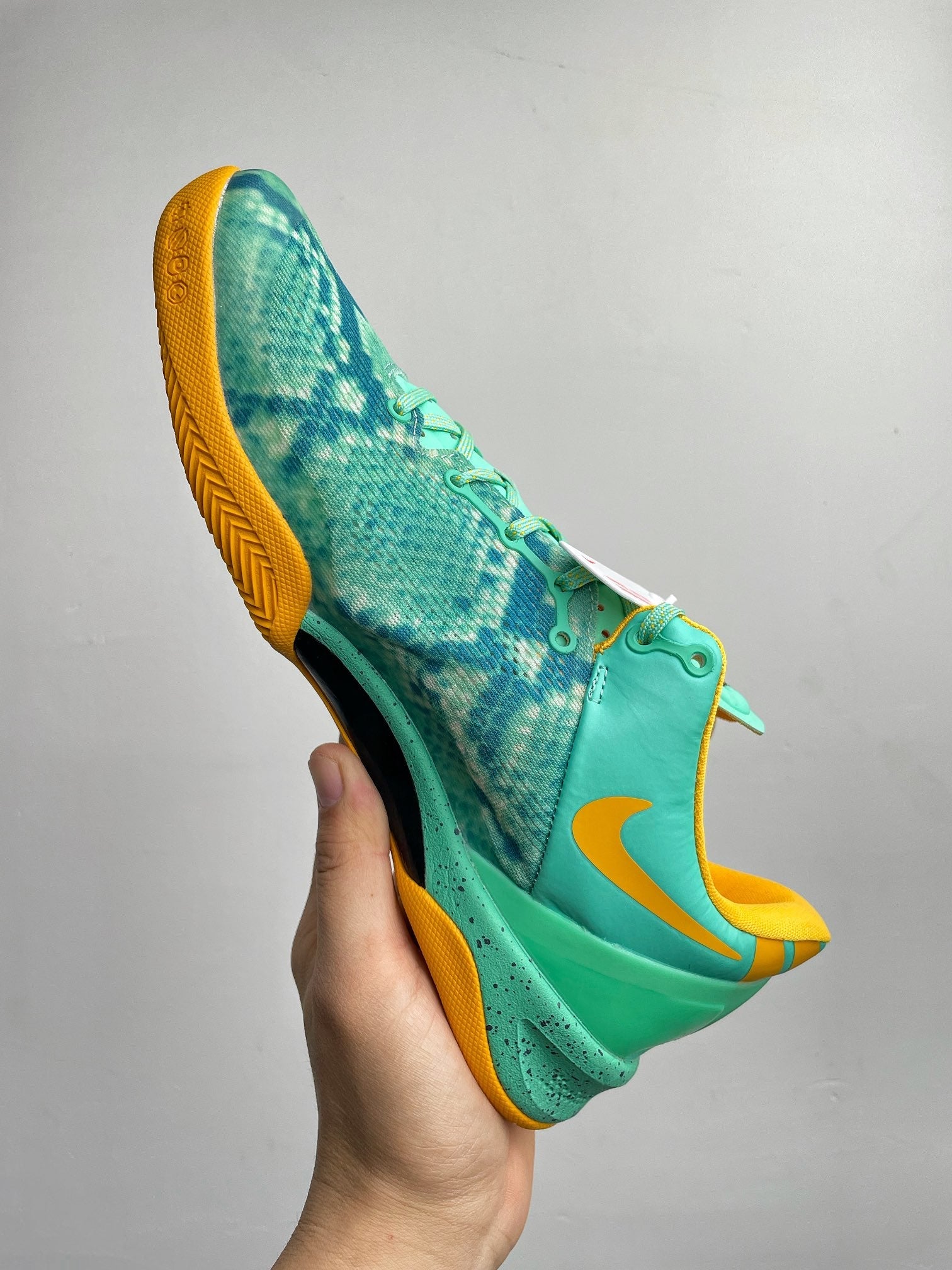 Teal basketball shoe side view with yellow sole and swoosh, lace-up