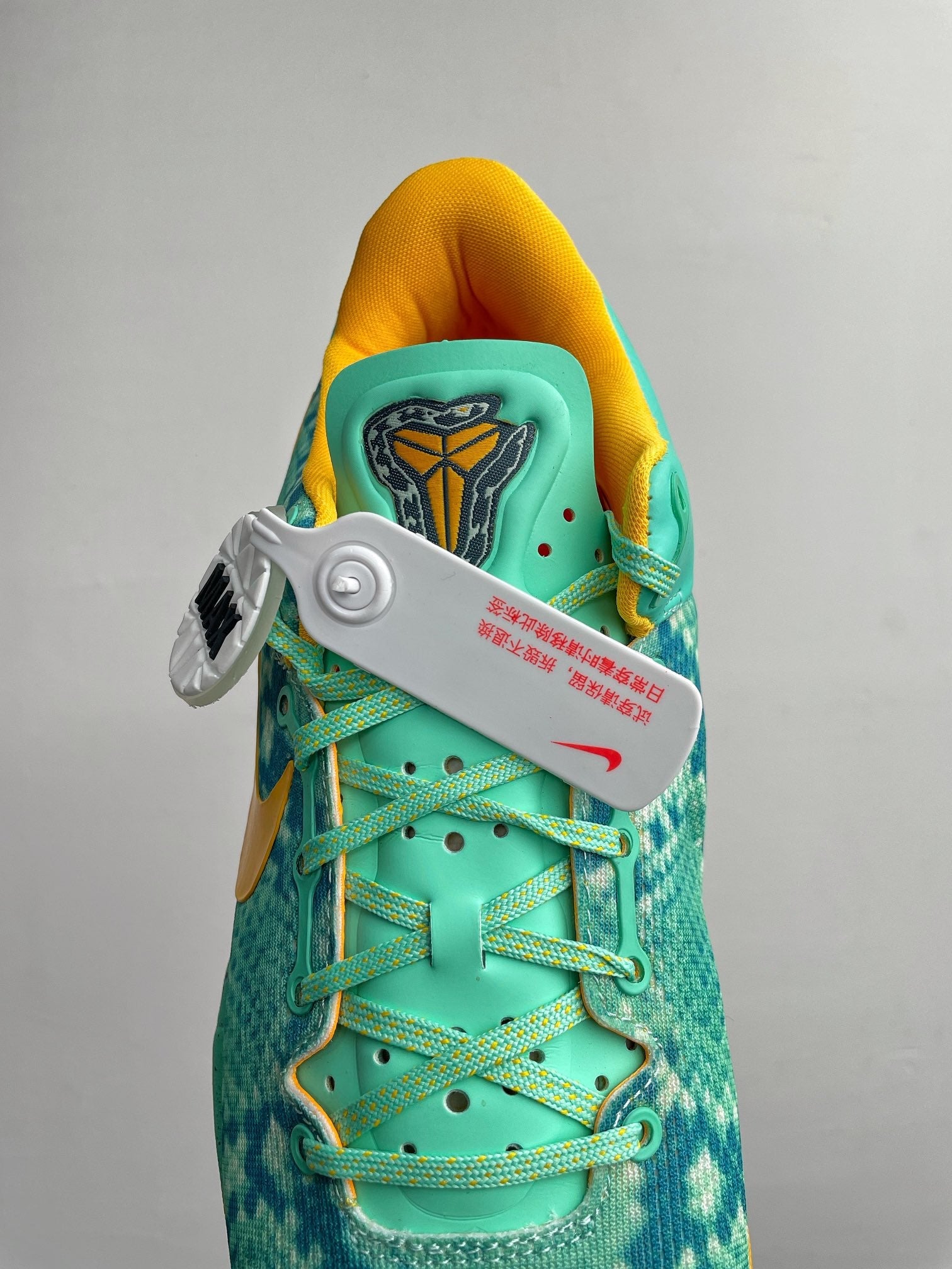 Teal basketball shoe with laced upper, yellow ankle lining, and tongue logo