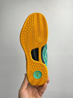 Basketball shoe outsole in yellow with grip tread and teal side label