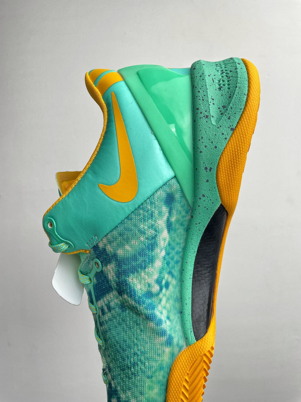 Teal basketball shoe with yellow collar lining and textured side panels