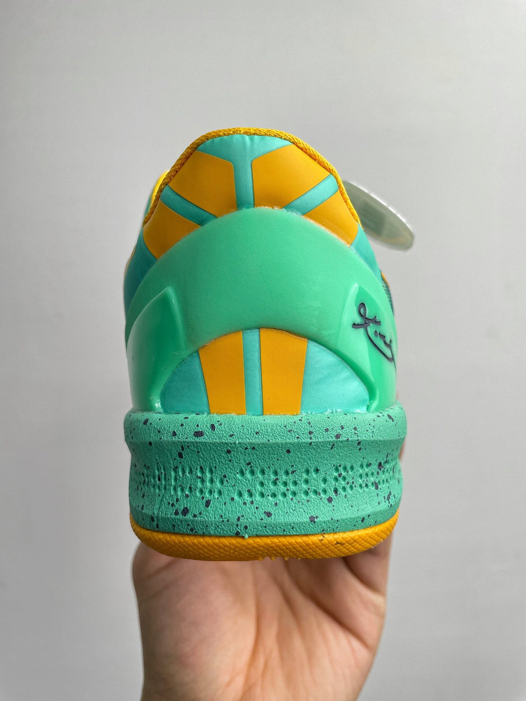 Teal basketball shoe heel with yellow insole panel and lace-up eyelets