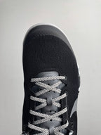 Front view of black Nike basketball shoe with gray laces and Swoosh overlay