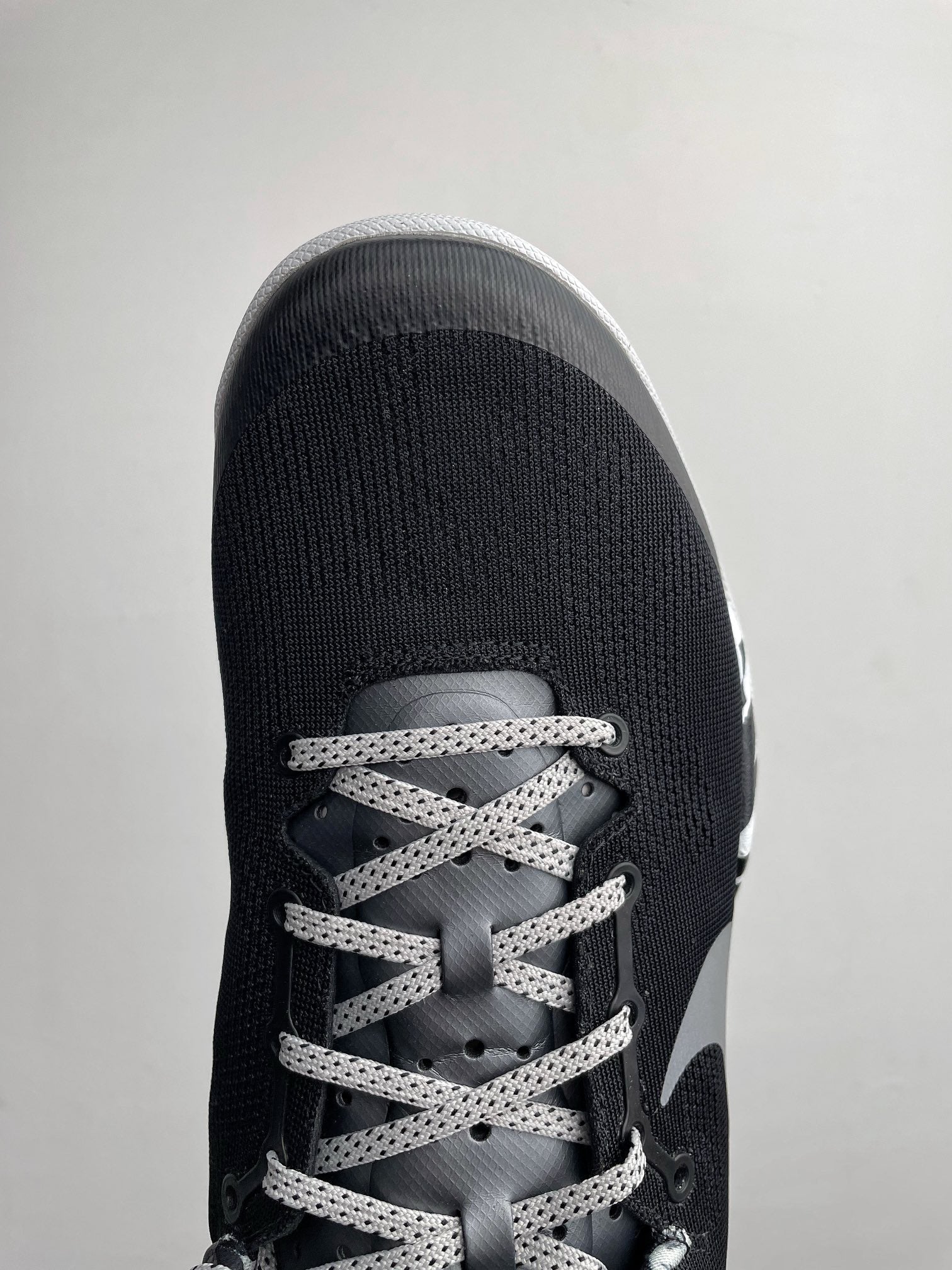 Front view of black Nike basketball shoe with gray laces and Swoosh overlay