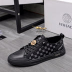Black sneakers with monogram-style pattern, lace-up front, gold coin emblem on strap