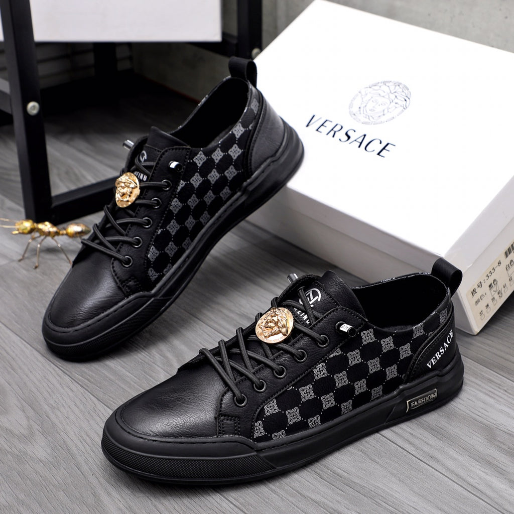 Black low-top sneakers with patterned side panels, lace-up front, gold emblem detail