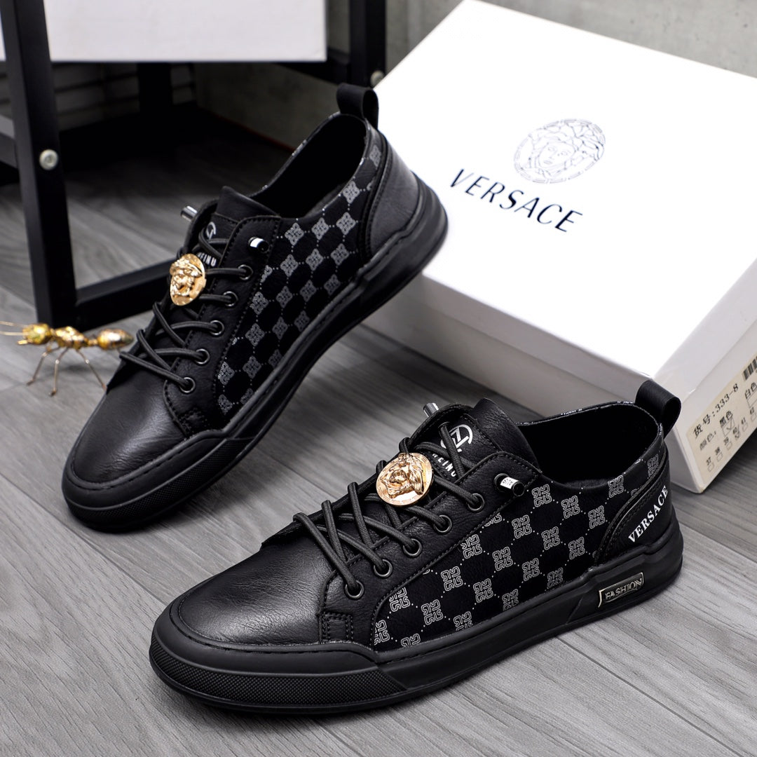 Black low-top sneakers with patterned side panels, lace-up front, gold emblem detail