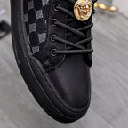 Close-up black sneakers; lace-up front, textured sole edge, gold emblem hardware detail