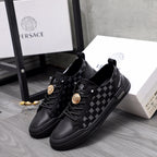 Pair of black low-top sneakers with patterned panels and gold emblem accents, lace-up