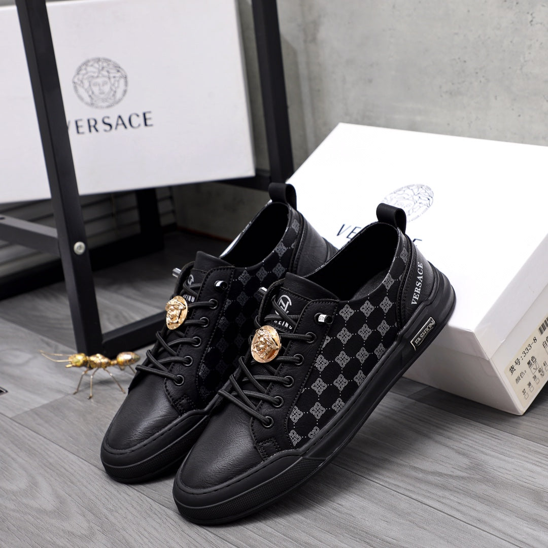 Pair of black low-top sneakers with patterned panels and gold emblem accents, lace-up