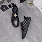 Black sneakers with patterned side panel, lace-up front, gold emblem strap; low sole
