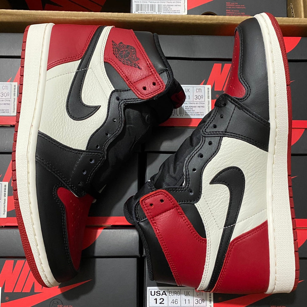 Pair of black, white, and red high-top sneakers with lace strap and Nike Swoosh.