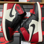 Pair of black, white, and red high-top sneakers with lace strap and Nike Swoosh.