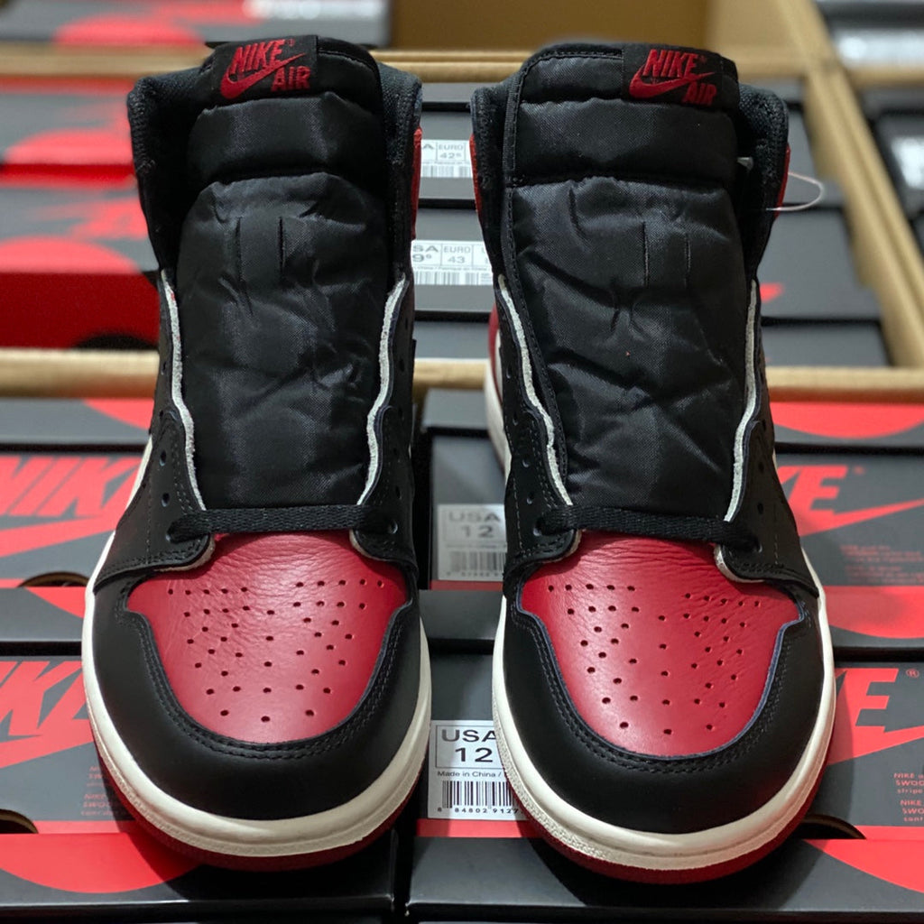 Black and red high-top sneakers with padded ankle, white midsole, and perforated toe.